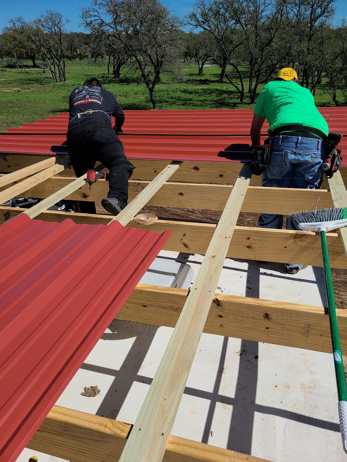 Crew installing red corrugated metal roofing panels
