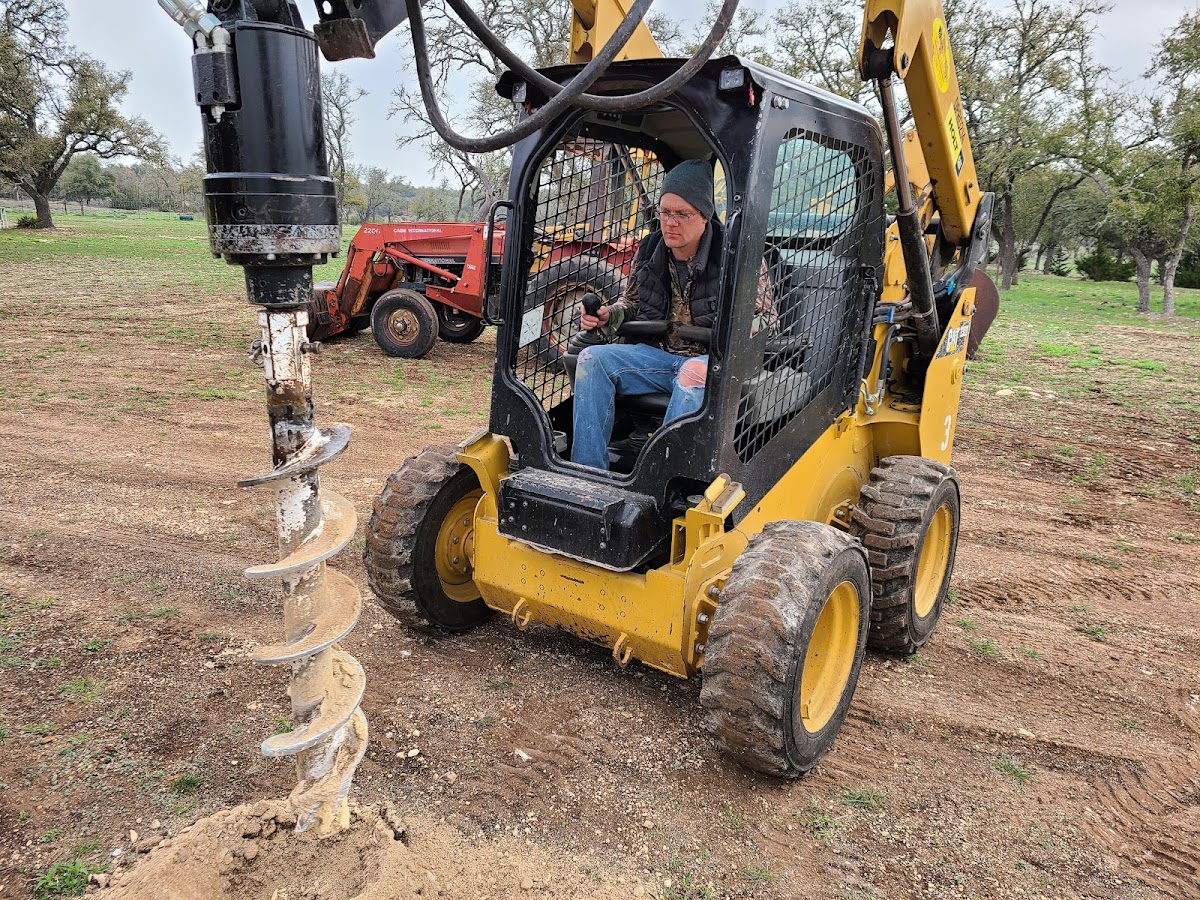 Taylor operating a skid steer with auger attachment drilling post holes